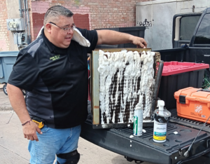 Aric with Jade Air cleaning the condenser of an HVAC unit